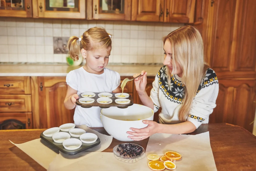 Little girl helping her sister bake cookies in a cozy kitchen